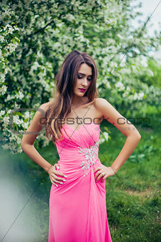 Portrait of young beautiful woman posing among spring blooming trees.
