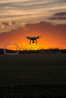 Drone silhouetted against orange sunset