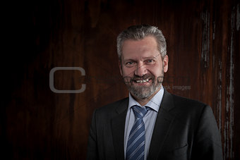 Portrait of a mature smiling businessman on black background