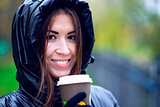 Girl in jacket with hood, holding a coffee or tea, young enjoys the outdoors and sports, spring  autumn, lifestyle, black , smiling brunette in gloves