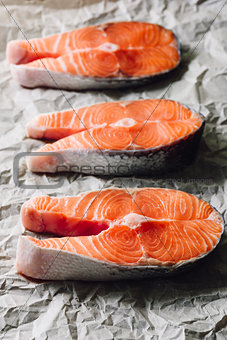Three Raw Salmon Steaks on Parchment Paper