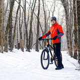 Mountain Biker with Bike on the Snowy Trail in Beautiful Winter Forest