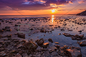 Exciting  rocky coast sunset with water reflection