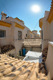 View among yellow houses on the roof tiles and second floors with towers. Spain.