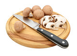 Knife with sliced and whole chestnut mushrooms on chopping board