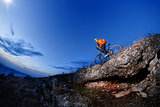 Cyclist Riding the Bike Down Hill on the Mountain Rocky at Sunset.