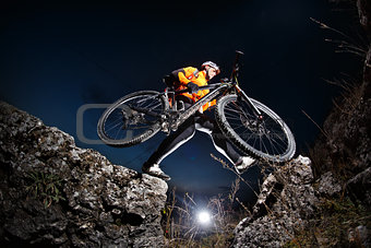Athlete jumping across rocks with his bicycle