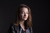 Young woman in leather jacket rock style over black background