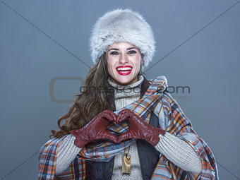 smiling woman isolated on cold blue showing heart shaped hands