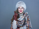 smiling elegant woman in fur hat isolated on cold blue got idea