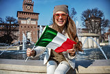 tourist woman near Sforza Castle in Milan, Italy showing flag