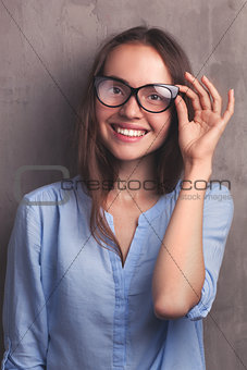 portrait of beautiful happy young woman with glasses near grey background wall
