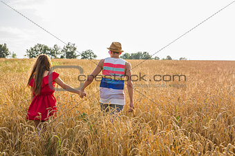 Back view of amorous couple walking in the field