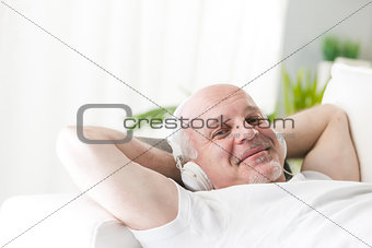 mature man relaxing with music on the sofa