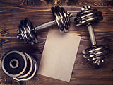 Toned image of metal dumbbells and a sheet of craft paper