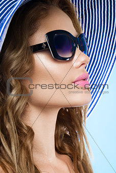 Beautiful young woman in elegant hat and sunglasses