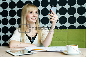 Girl sitting in cafe holds a smartphone