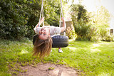 Portrait Of Young Girl Playing On Tire Swing In Garden