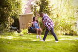 Father Pushing Daughter On Tire Swing In Garden