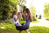 Two Girls Sitting On Swing Playing Clapping Game
