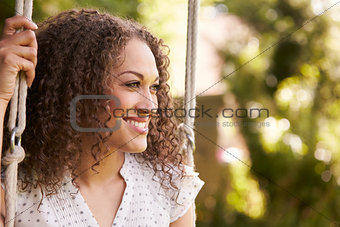 Head And Shoulders Shot Of Mid Adult Woman Sitting On Swing
