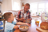 Father And Son At Home Eating Breakfast In Kitchen Together