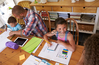 Parents Helping Children With Homework At Table