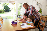 Father Helping Children With Homework At Table