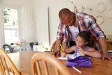 Father Helping Daughter With Homework At Table