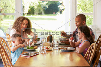 Family At Home Eating Meal In Kitchen Together