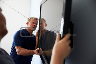 Two Men Fitting Flat Screen Television To Wall