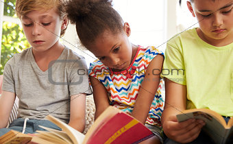 Close Up Of Children Reading On Window Seat