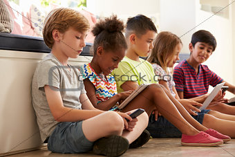 Group Of Children Sit On Floor And Use Technology