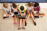Overhead Shot Of Children Sitting On Floor Using Technology
