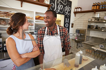 Couple working at a sandwich bar looking at each other