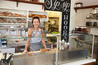 Woman behind the counter of sandwich bar looking to camera