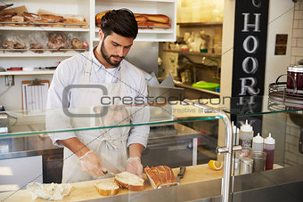 Man preparing food behind the counter at a sandwich bar
