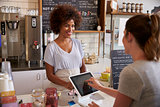 Customer at counter of coffee shop pays using touch screen