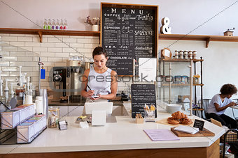 Waitress writing customerÕs order at counter of coffee shop