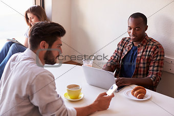 Young adults using mobile technology at a coffee shop