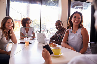 Five adult friends sitting in a cafe, over shoulder view