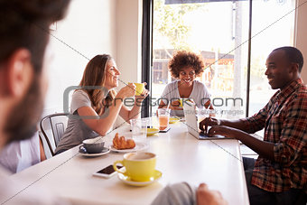 Five adult friends sitting in a cafe, over shoulder view