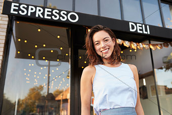 Young woman business owner standing outside cafe shopfront