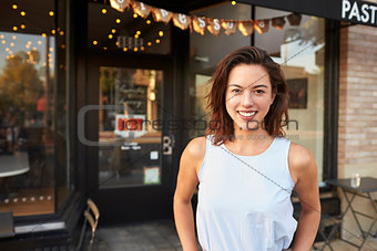 Female business owner standing in the street outside cafe