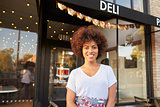 Black female business owner standing in street outside cafe