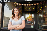 Female business owner stands outside cafe with arms crossed