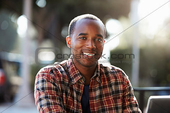 Young black man sitting outdoors, portrait