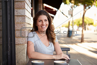 Young woman sitting at a table outside a cafe