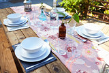 Table Set For Outdoor Meal On Wooden Table In Garden