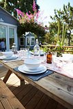 Table Set For Outdoor Meal On Wooden Table In Garden